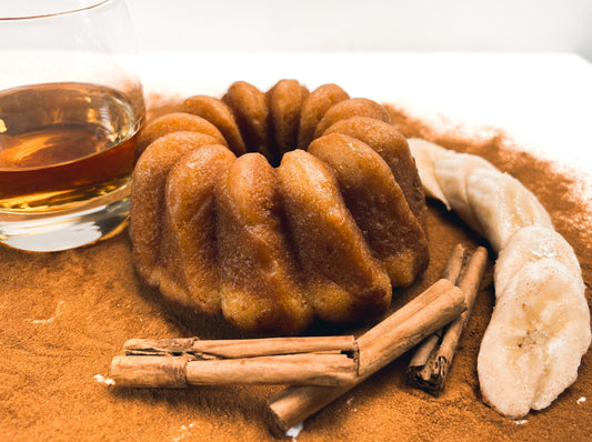 A photo of rum cake with cinnamon, fresh bananas and a glass of whiskey