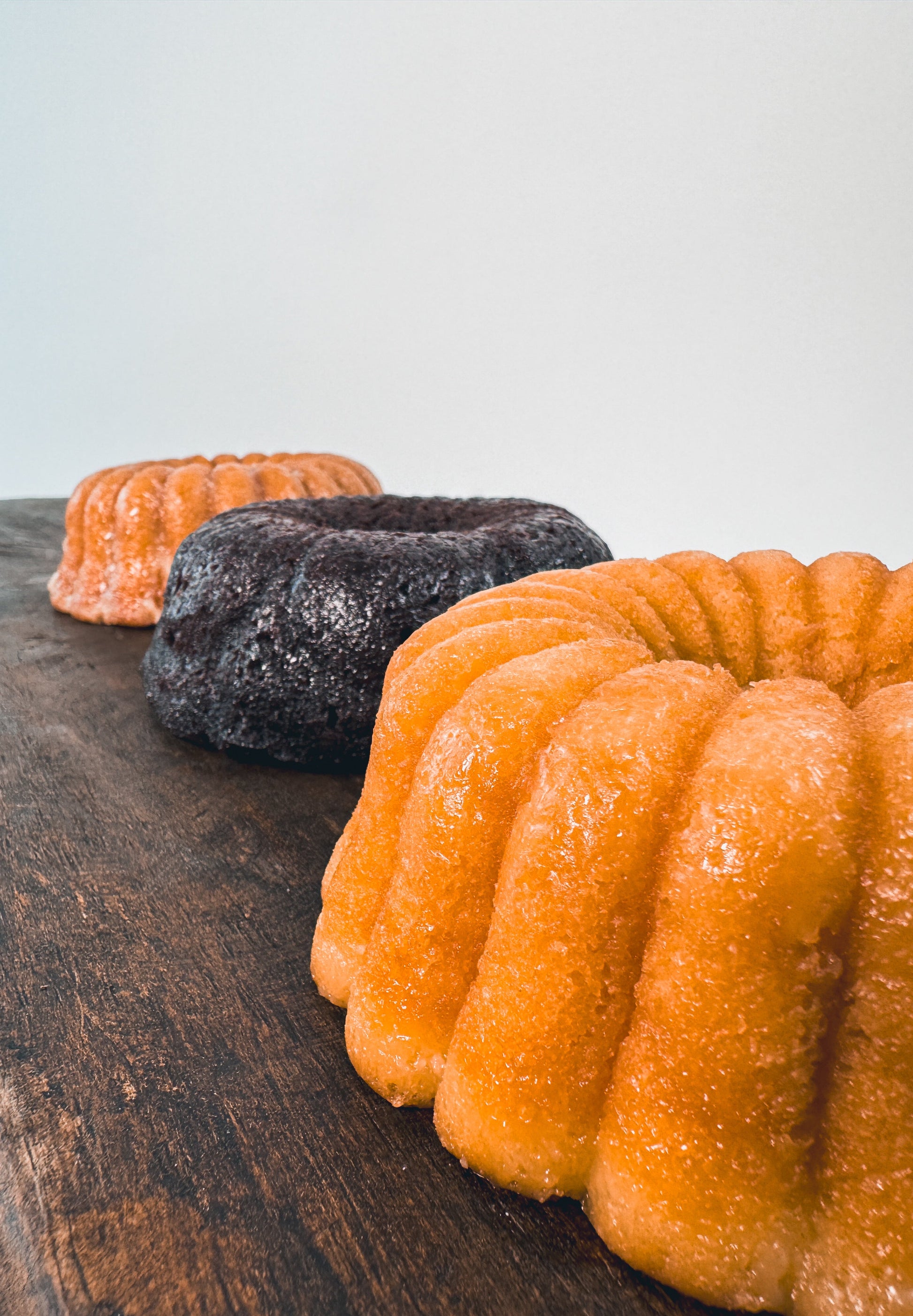Vanilla rum cake, chocolate rum cake and cinnamon banana whiskey cake on a wooden board with a white background
