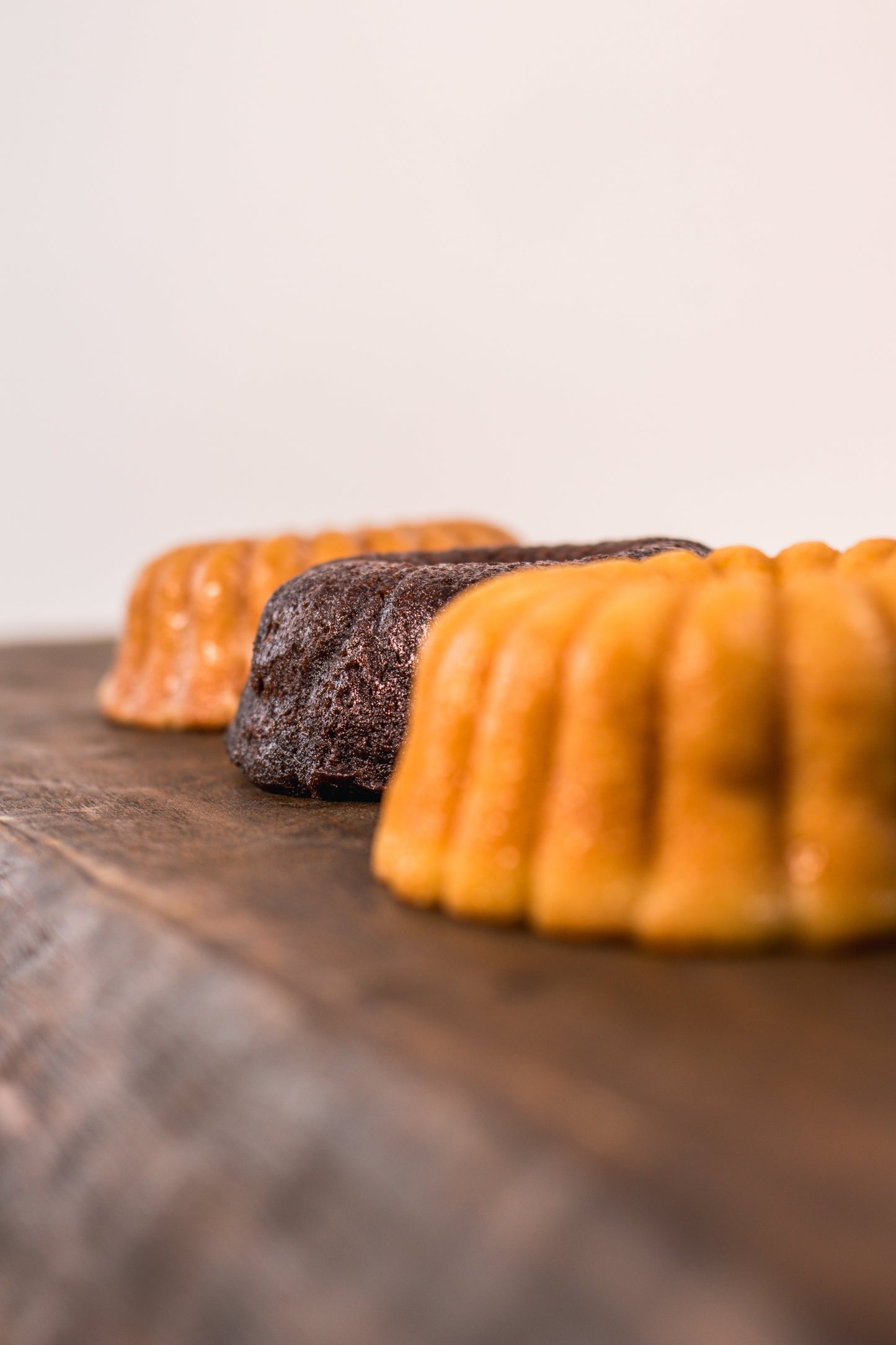 Vanilla rum cake, chocolate rum cake and cinnamon banana whiskey cake on a wooden board with a white background