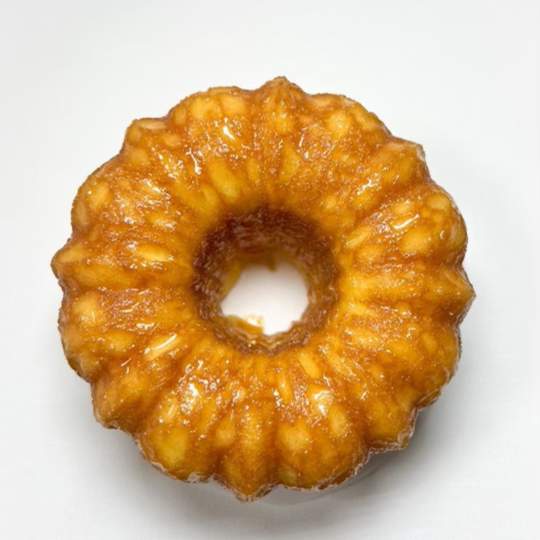 Top-down photo of a vanilla rum cake with a golden-brown crust, drizzled with glaze on a white background